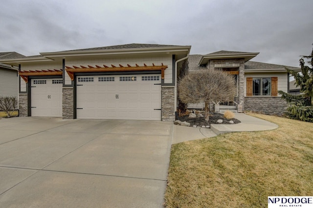 prairie-style home with driveway, stone siding, board and batten siding, an attached garage, and a front yard