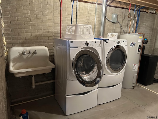 laundry room with brick wall, water heater, laundry area, independent washer and dryer, and a sink