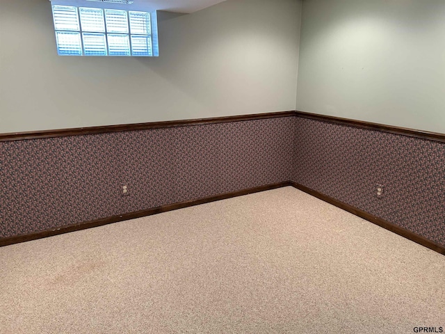 empty room featuring wallpapered walls, a wainscoted wall, and carpet floors