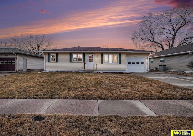 ranch-style house with concrete driveway, a yard, and a garage