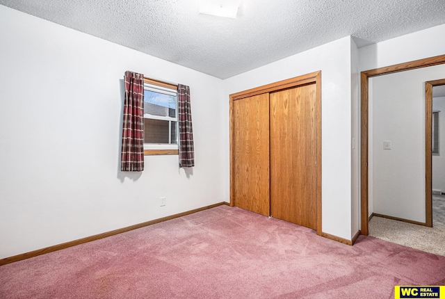 unfurnished bedroom with a closet, light colored carpet, a textured ceiling, and baseboards