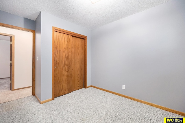 unfurnished bedroom featuring a closet, baseboards, a textured ceiling, and carpet