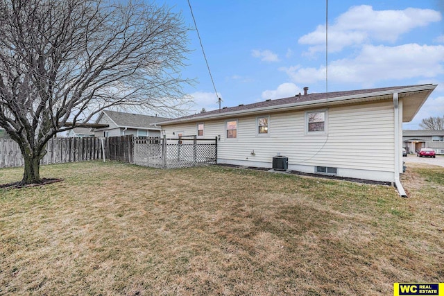 back of property with central air condition unit, a lawn, and fence