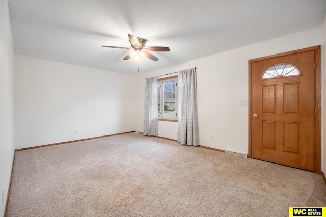 carpeted entrance foyer featuring a ceiling fan, visible vents, and baseboards