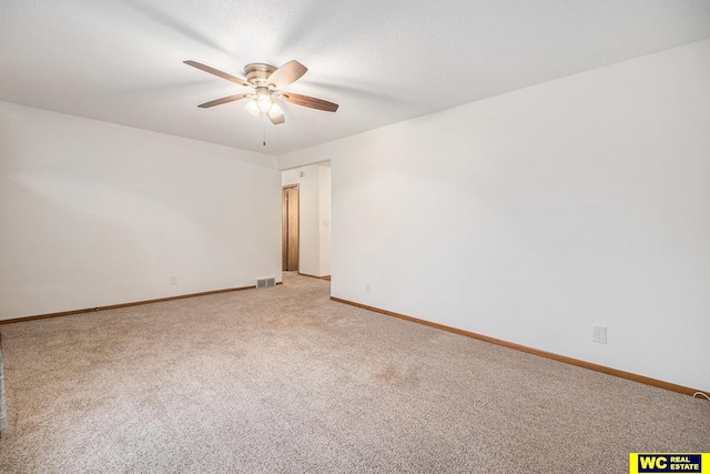 spare room featuring visible vents, baseboards, ceiling fan, light colored carpet, and a textured ceiling