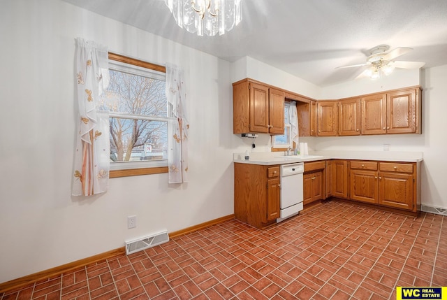 kitchen with visible vents, a sink, white dishwasher, light countertops, and baseboards