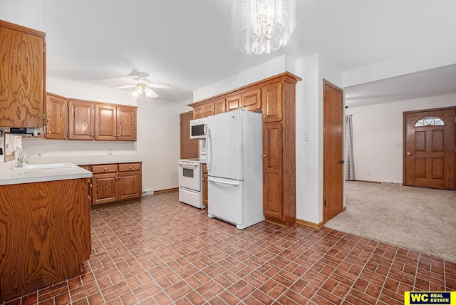 kitchen with white appliances, light countertops, baseboards, and a sink