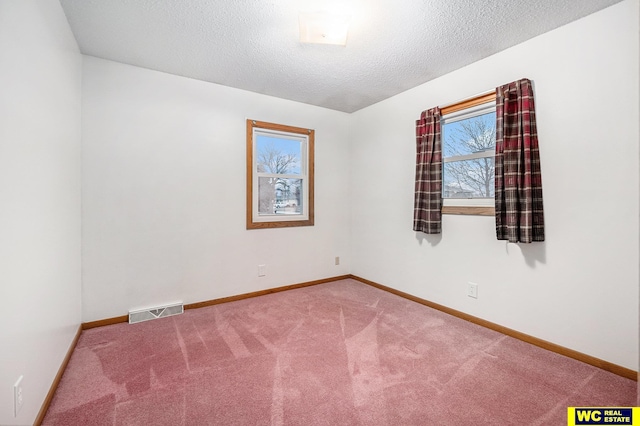 carpeted spare room with visible vents, a textured ceiling, and baseboards