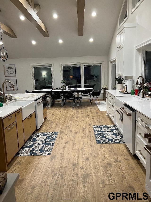 kitchen with dishwasher, stainless steel dishwasher, light wood-style floors, white cabinetry, and a sink