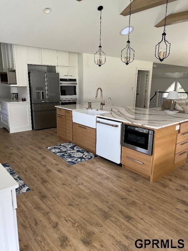 kitchen with a spacious island, dark wood finished floors, a sink, hanging light fixtures, and appliances with stainless steel finishes