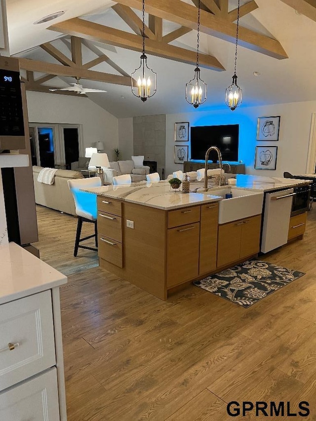 kitchen with light wood finished floors, a sink, open floor plan, and white dishwasher