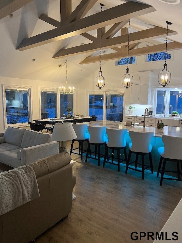 interior space featuring beam ceiling, high vaulted ceiling, dark wood-style flooring, and a chandelier