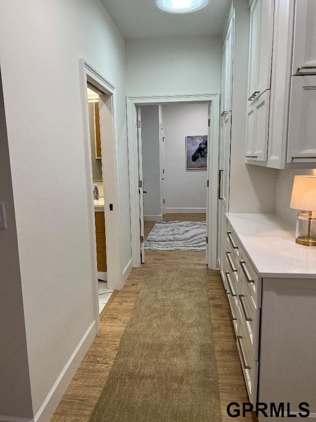 hall featuring light wood-style floors and baseboards