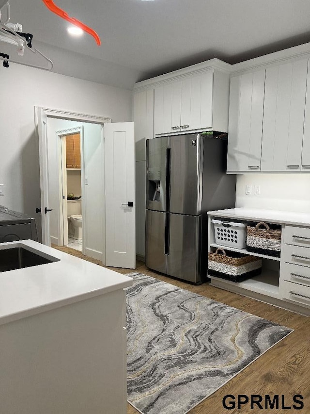 kitchen featuring light countertops, white cabinets, stainless steel fridge with ice dispenser, and light wood-style floors