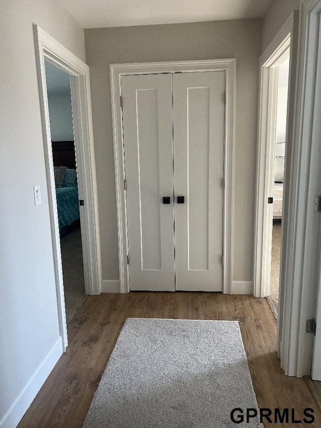 hall with baseboards and wood finished floors