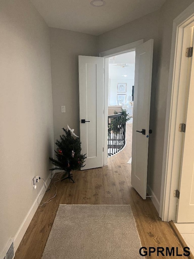 corridor with wood finished floors, visible vents, and baseboards