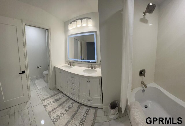 bathroom with double vanity, marble finish floor, toilet, and a sink