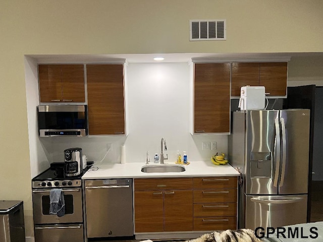 kitchen featuring visible vents, stainless steel appliances, light countertops, and a sink