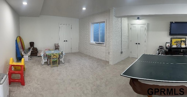 rec room featuring recessed lighting, carpet, and brick wall