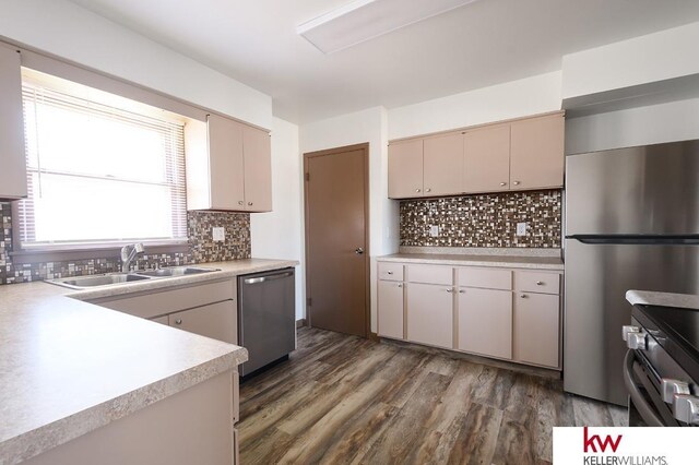 kitchen featuring a sink, appliances with stainless steel finishes, dark wood-style floors, and light countertops