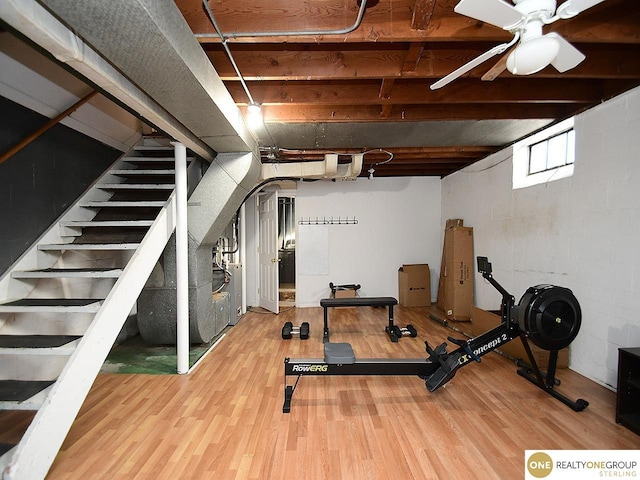 workout room featuring concrete block wall, wood finished floors, and ceiling fan