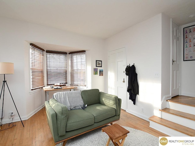 living room with light wood-type flooring, baseboards, and stairs