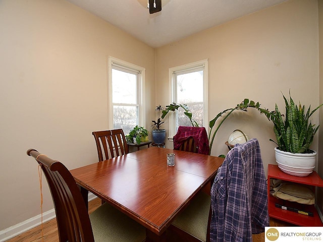 dining space with baseboards and wood finished floors