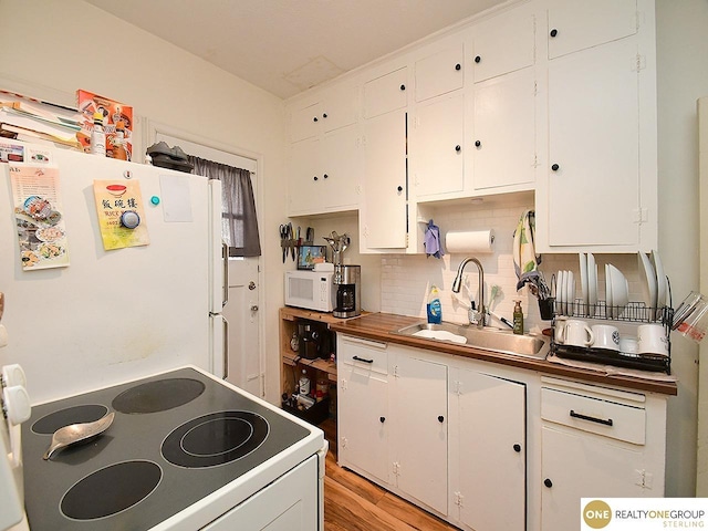 kitchen with light wood-type flooring, a sink, tasteful backsplash, white cabinetry, and white appliances