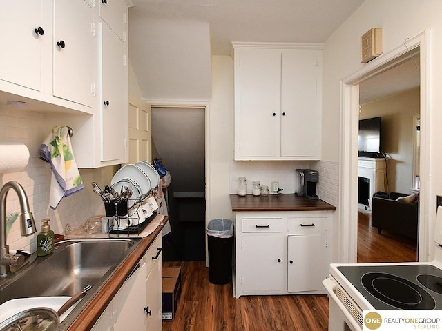 kitchen with dark wood-style floors, electric range, a sink, white cabinets, and backsplash