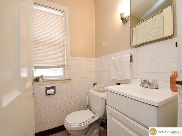 full bathroom featuring vanity, tile walls, toilet, and a wainscoted wall