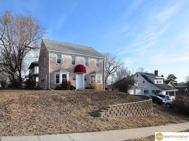 colonial home featuring brick siding and an attached garage