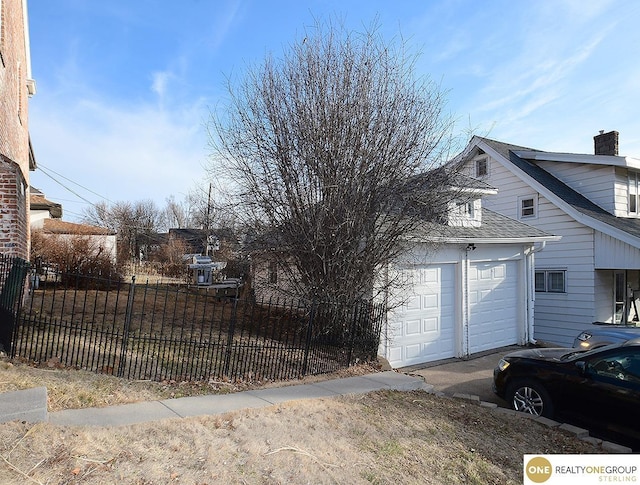 view of home's exterior with a fenced front yard, driveway, roof with shingles, and a chimney