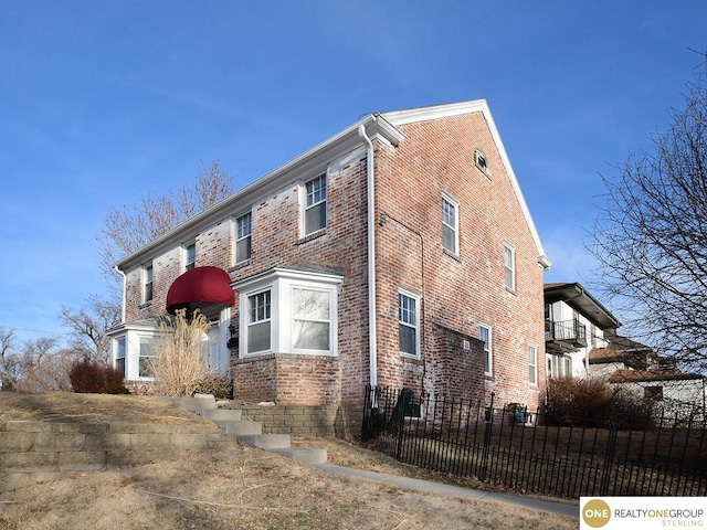 view of home's exterior featuring brick siding and fence