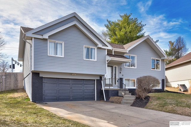 raised ranch featuring brick siding, concrete driveway, fence, and a garage