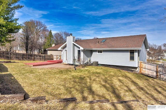 back of property featuring a fenced backyard, central AC, a chimney, and a yard