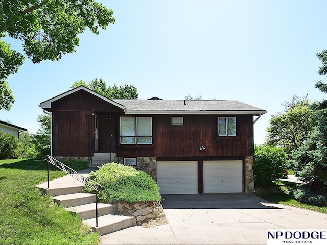 view of front of house with an attached garage, stone siding, concrete driveway, and a front yard