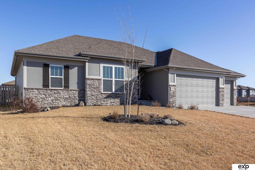 6217 S 200th Ave, Omaha, NE 68135 - view of front of home featuring stone siding, a front yard, concrete driveway, and an attached garage
