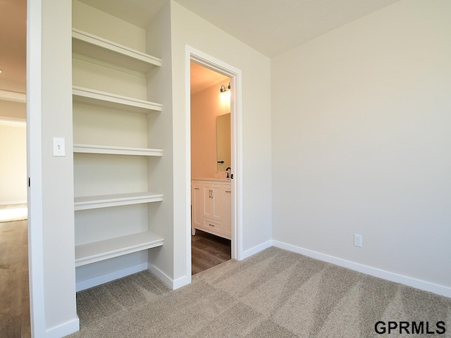 unfurnished bedroom with baseboards, carpet, and ensuite bathroom