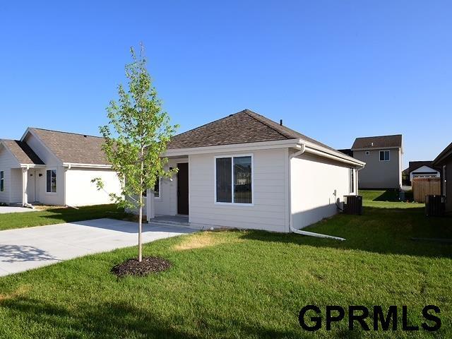 single story home featuring a front lawn, cooling unit, and a shingled roof