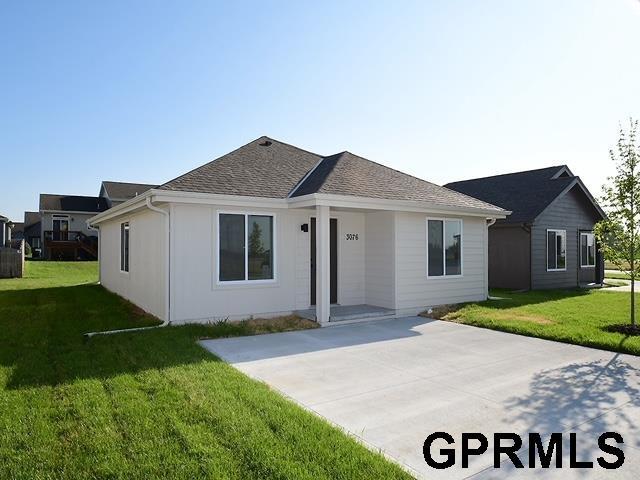 ranch-style home with roof with shingles and a front lawn