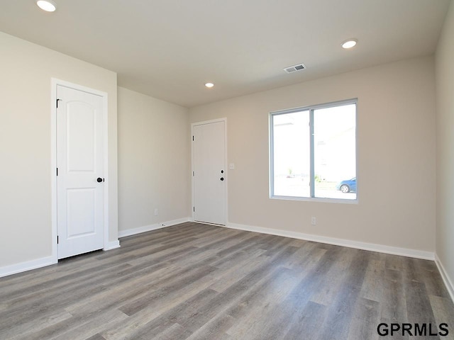 empty room featuring recessed lighting, visible vents, baseboards, and wood finished floors