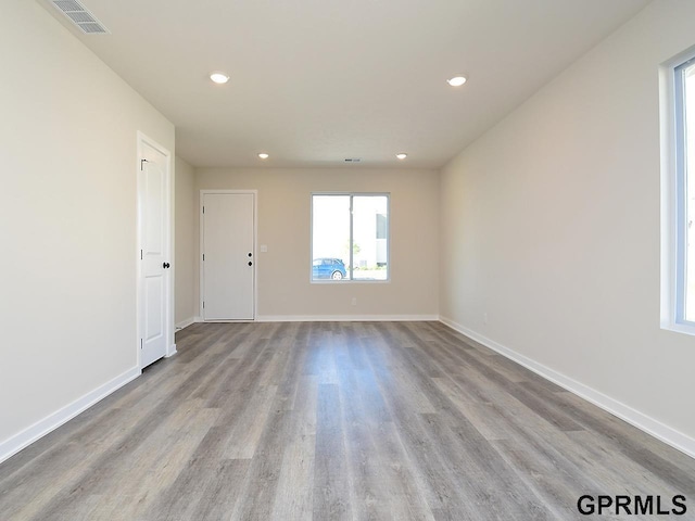 empty room featuring wood finished floors, baseboards, and visible vents