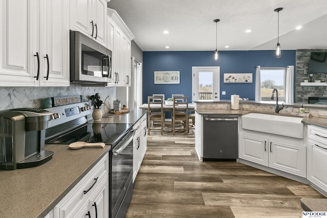 kitchen with dark wood-style flooring, a sink, stainless steel appliances, white cabinets, and backsplash
