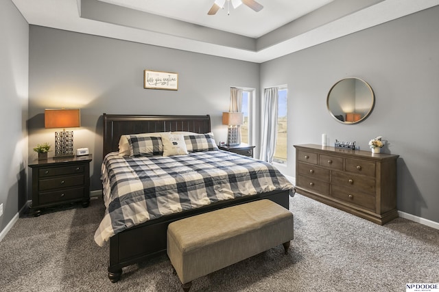 bedroom with a raised ceiling, carpet flooring, baseboards, and ceiling fan