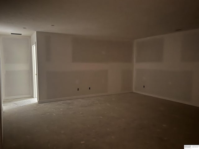 empty room featuring concrete flooring, visible vents, and baseboards