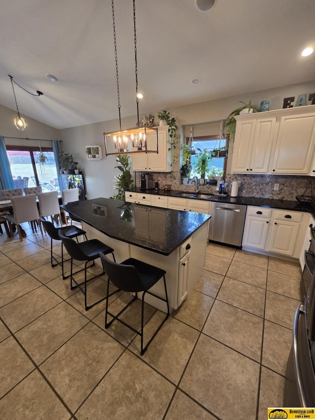 kitchen with a sink, stainless steel dishwasher, white cabinetry, light tile patterned flooring, and decorative backsplash