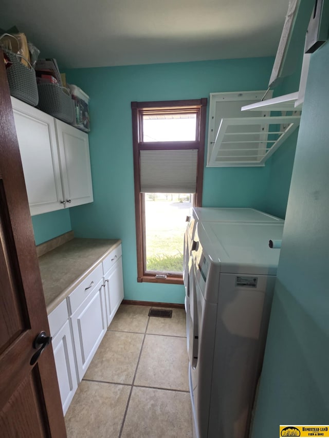 clothes washing area featuring light tile patterned floors, visible vents, baseboards, cabinet space, and separate washer and dryer
