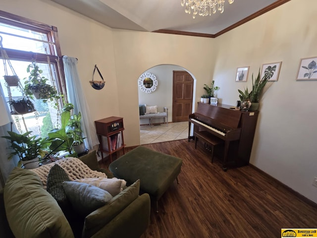 living area featuring a chandelier, arched walkways, wood finished floors, and ornamental molding