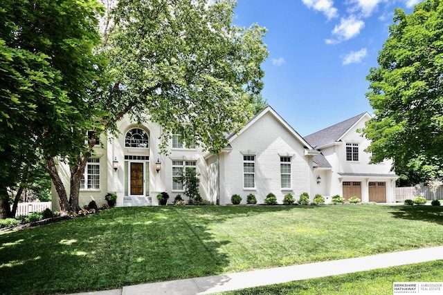 view of front of home featuring a front yard, an attached garage, fence, and brick siding