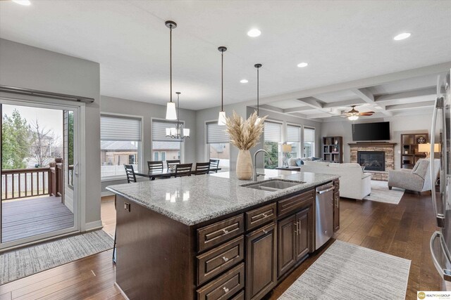 kitchen with a sink, ceiling fan with notable chandelier, recessed lighting, a fireplace, and stainless steel dishwasher